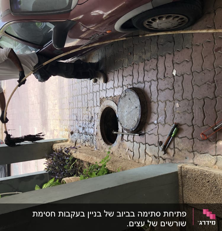 אדם מנקה ביוב עם מוט וכלים על הקרקע